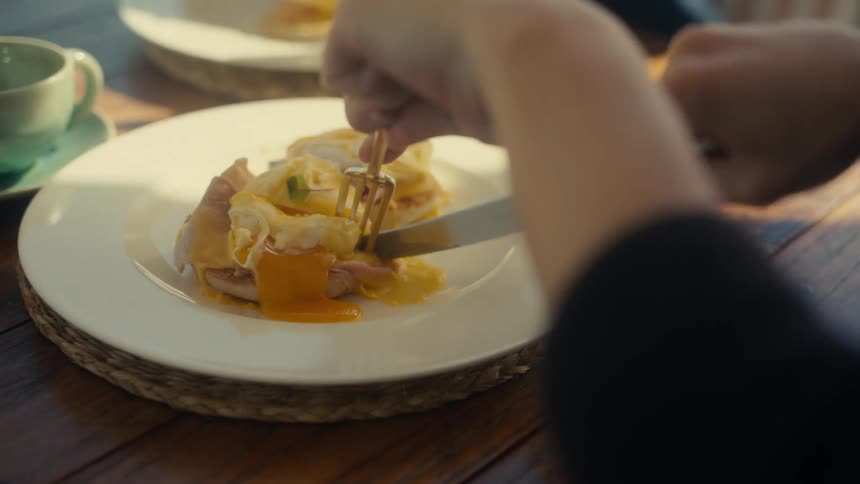 Woman cutting a plate of food with a fork and knife