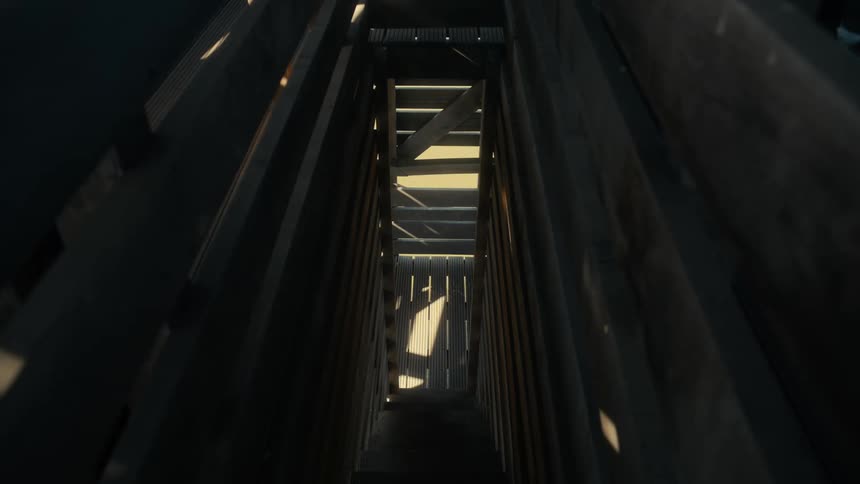 A narrow dimly lit staircase with wooden walls