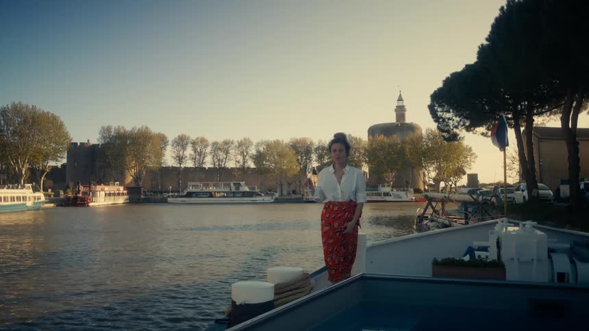 Woman sipping on a glass of champagne while standing at a marina on a lake in the late afternoon