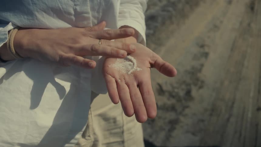 Close up of a womans hand interacting with salt in her palms