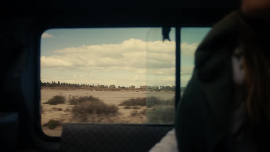 Woman traveling inside a vehicle in a desert landscape and talking