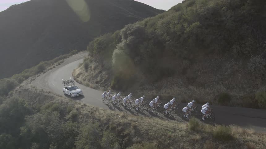 A team of bicyclists riding up a mountain road during the day