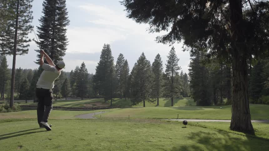 Golfer taking a big swing and sending a ball flying
