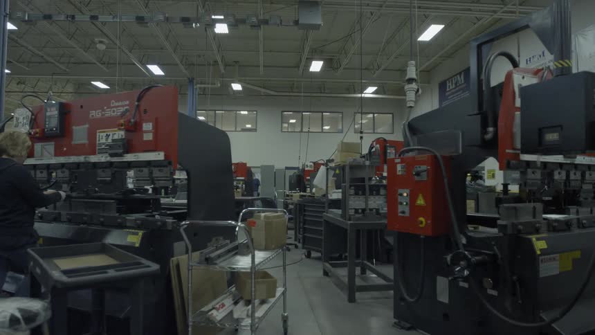 A woman operates machinery in an industrial shop
