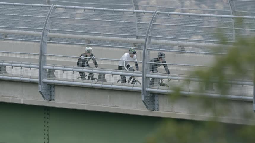 Bicyclists crossing a bridge  as traffic passes them