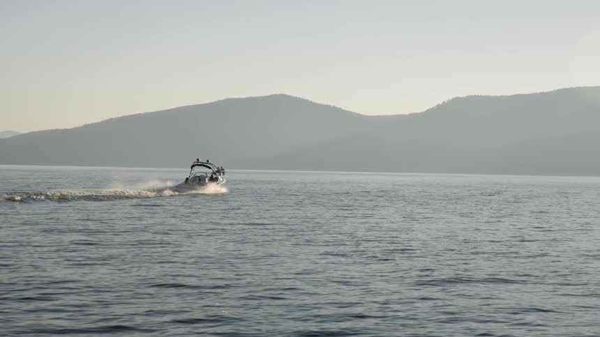A boat zooming across the water headed towards a mountain