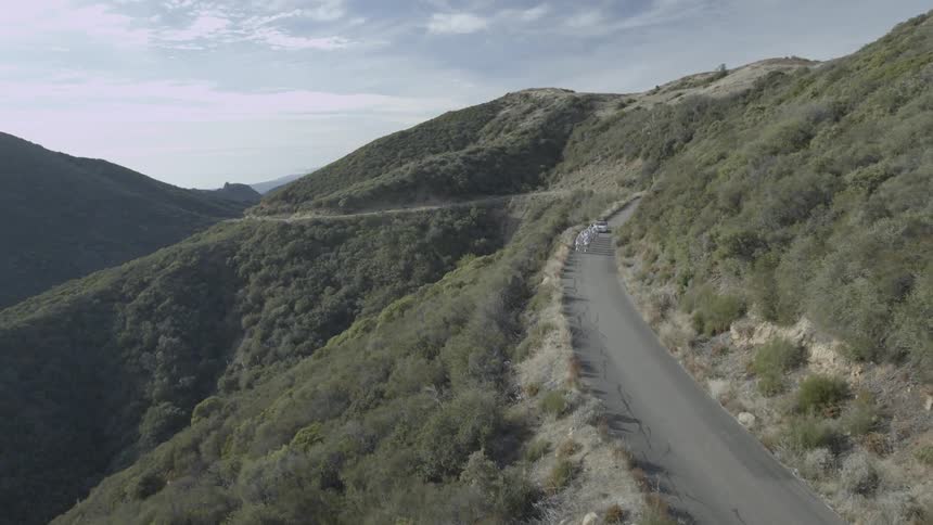 A chase vehicle follows a team of bicyclists on a mountain road