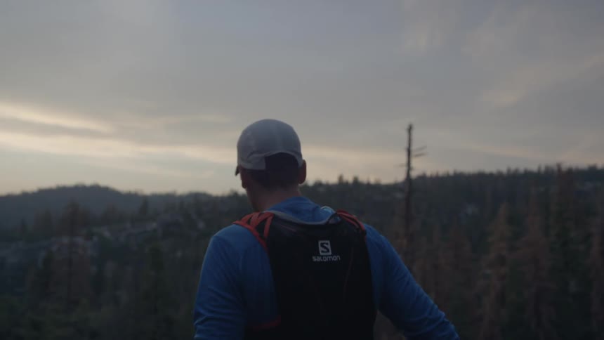 Hiker  running forward but then stopping to backup to take a look at the cloudy horizon