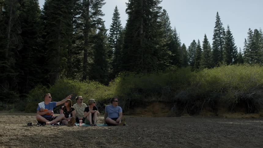 A group of people are sitting on a beach in a forested area