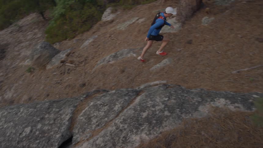 A man is jogging up a steep path in a natural setting