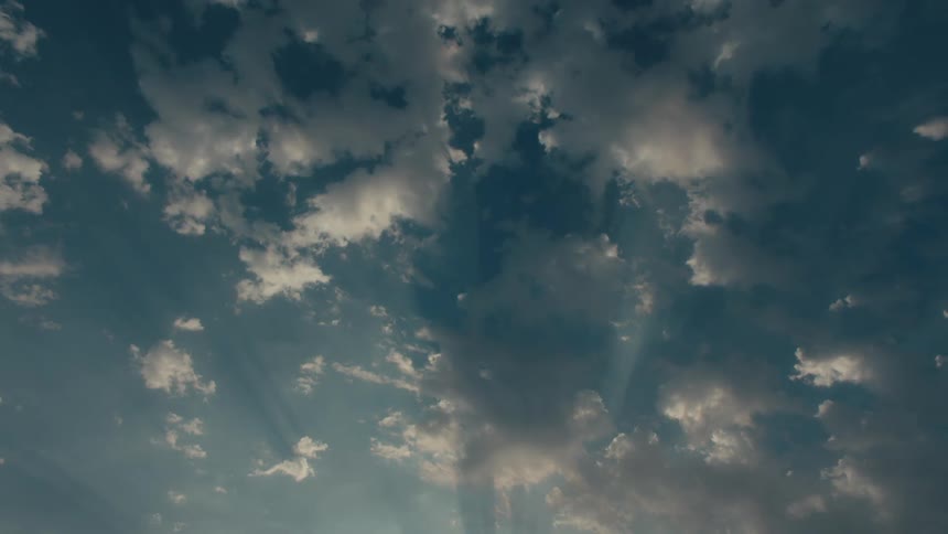A vast expanse of blue sky dotted with fluffy white clouds illuminated by the warm glow of the sun