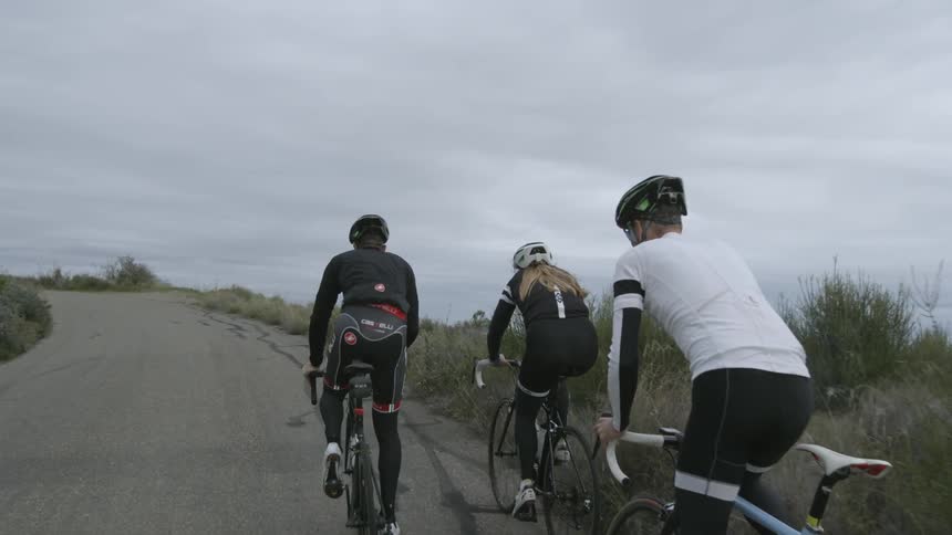 Three people are riding bicycles up a hill