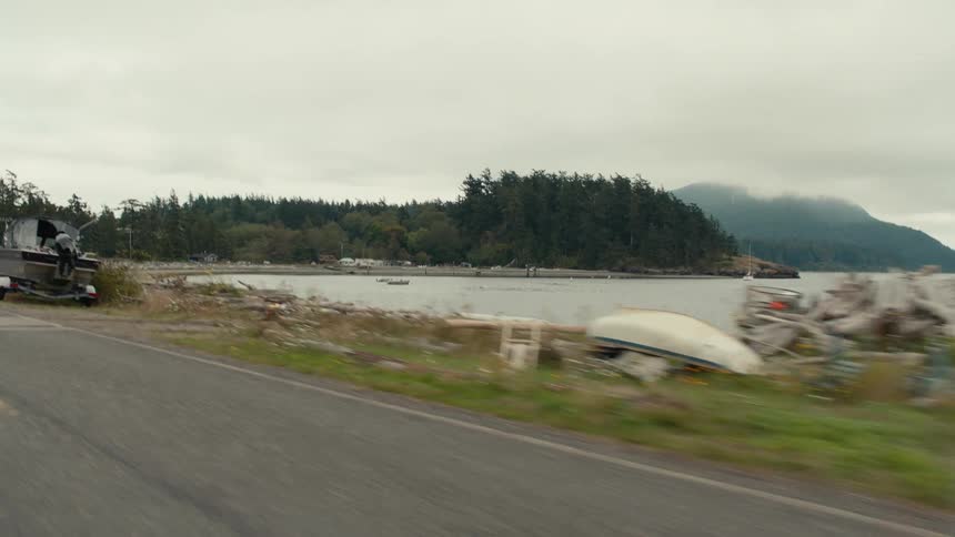 Boats and weathered wooden shacks stands beside a coastal road