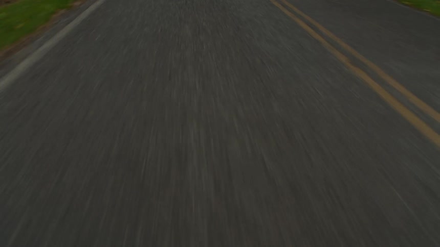 A view of a wet road with two yellow lines taken from a vehicles point of view