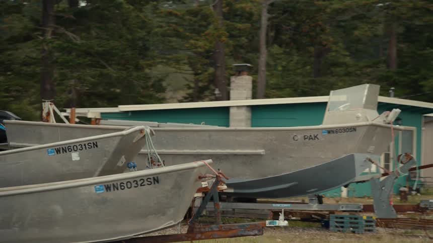 Metal boats on a wooden stand in an environment surrounded by trees