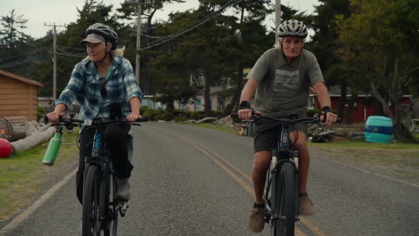 Elderly couple riding a bike during a cloudy day