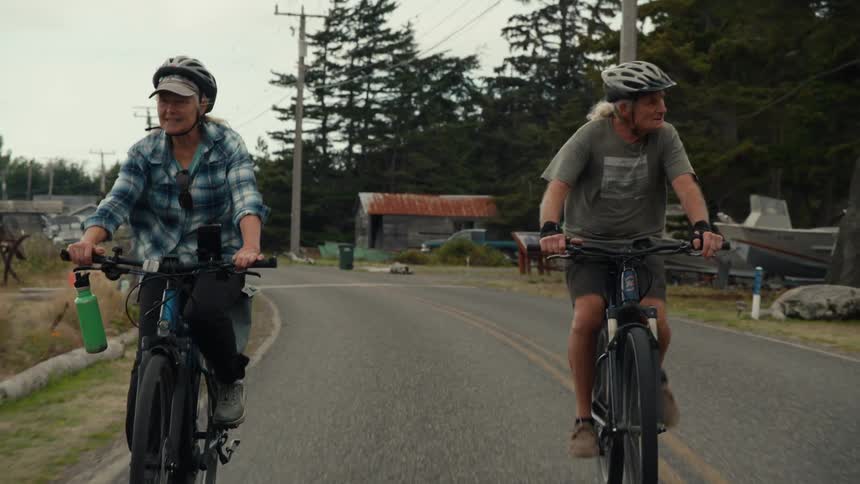 Elderly couple having fun riding bikes through a countryside area