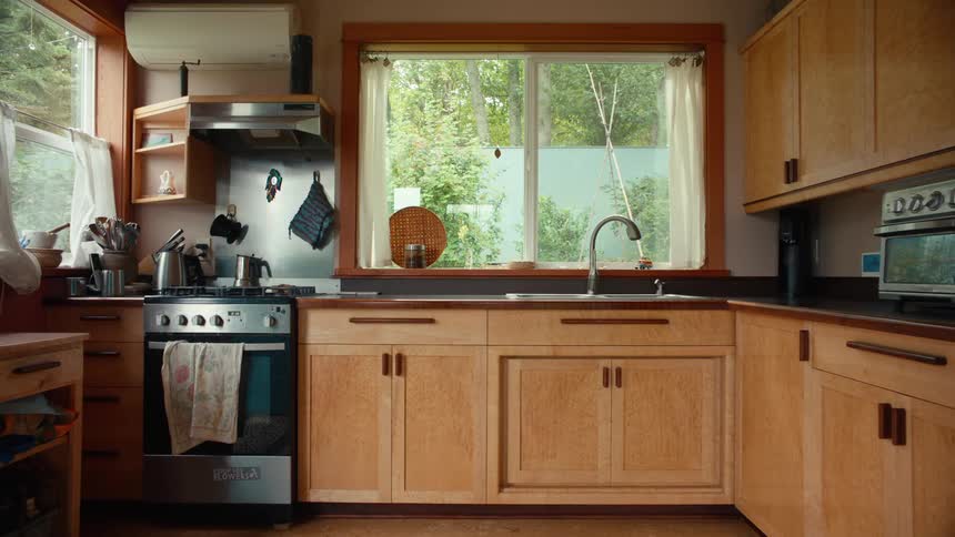 Wood and metal items compose the majority of the decor in a kitchen with two windows