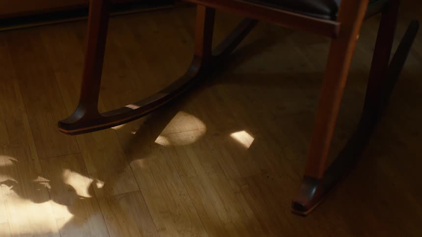 Downward view of the legs of a varnished wooden chair