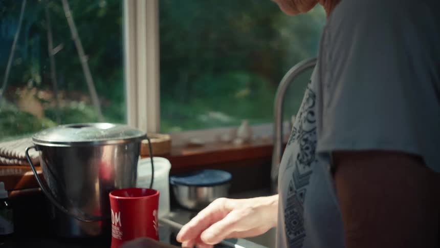 Elderly woman in the kitchen peeling garlic with a knife