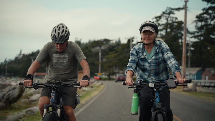 Elderly couple riding a bike on a paved street