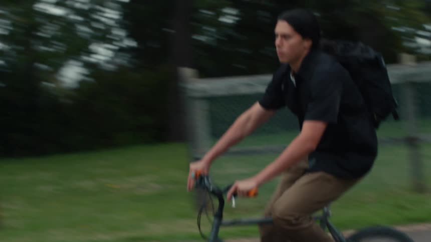 A native american teenager rides a bike around a court