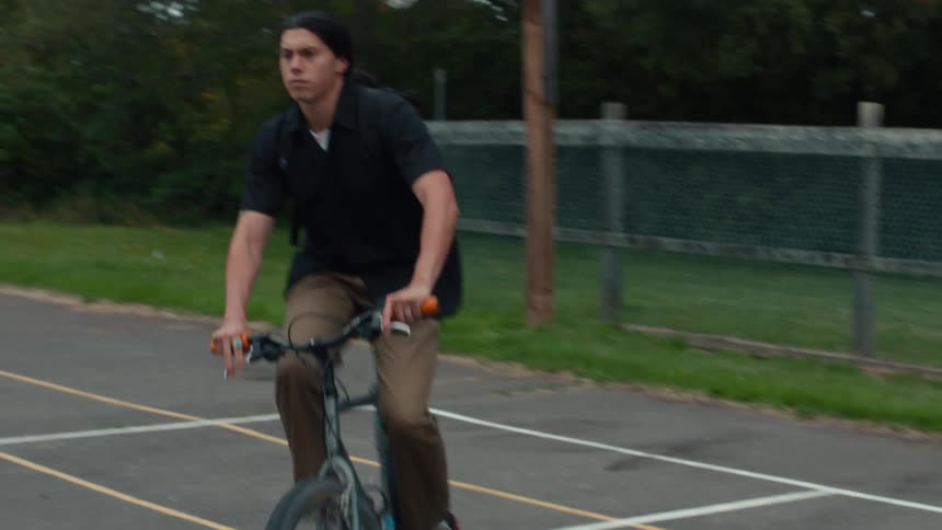 A young man rides his bicycle with focus and determination in a lush outdoor setting