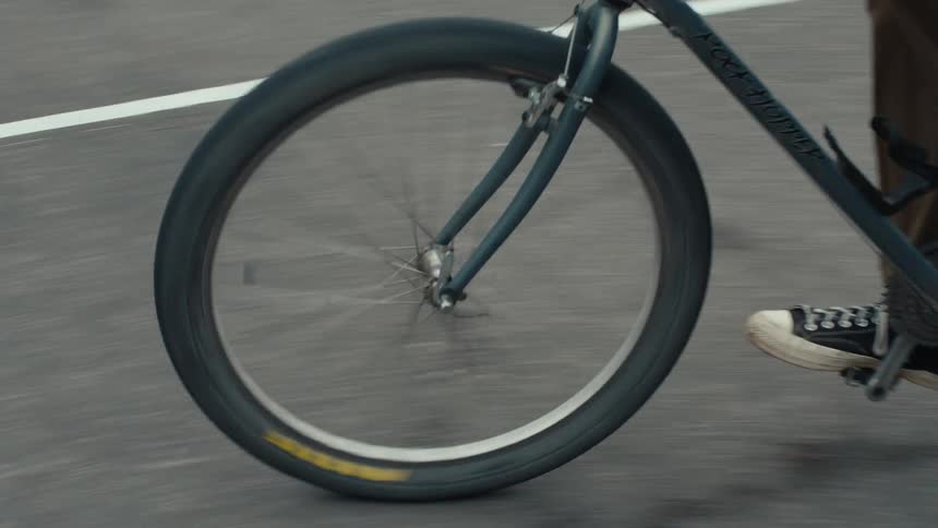 A cyclist navigates a bike along a paved path lined with yellow markings on a sports court