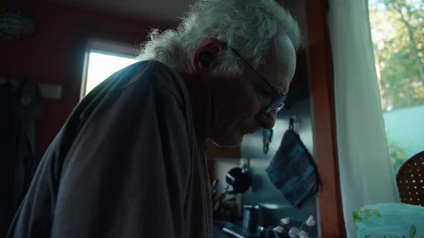 Man kneading dough in his kitchen near a window