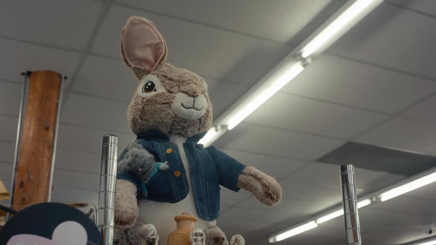 A large furry peter rabbit plush toy standing on a shelf in a store