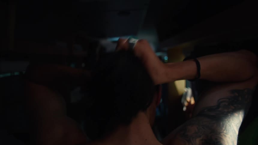 Back view of a shirtless man tying up his long hair