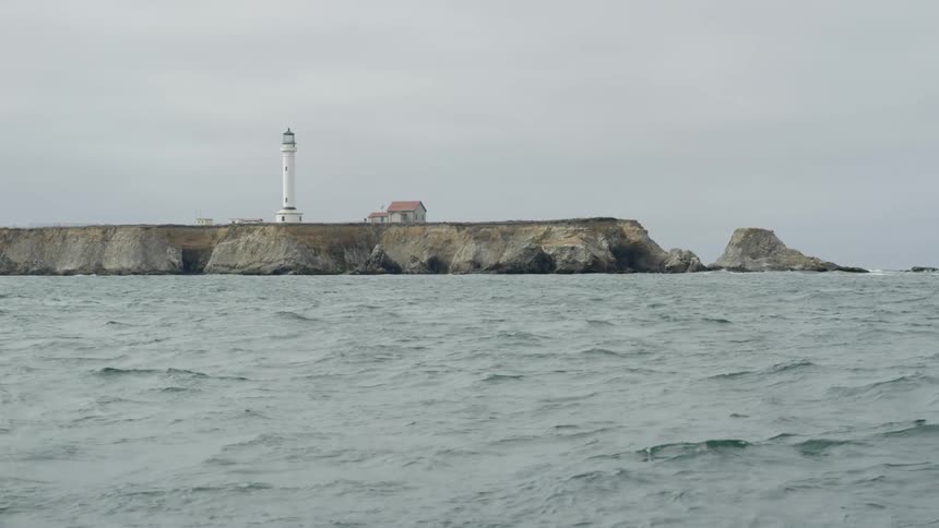 Lighthouse seen in the distance on elevated land on a cloudy day