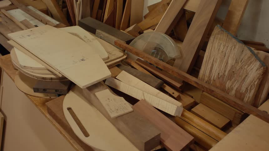 A workbench cluttered with various pieces of wood including cutouts and different types of lumber