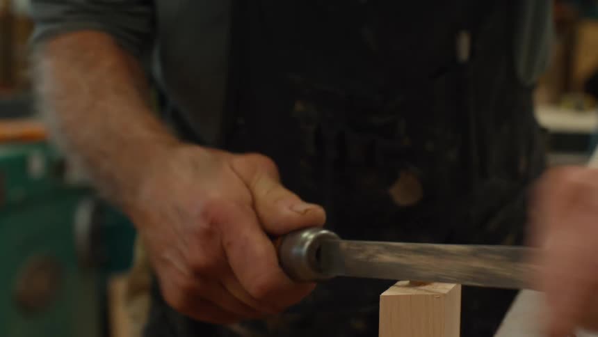 Carpenter with a tool shaping a piece of wood