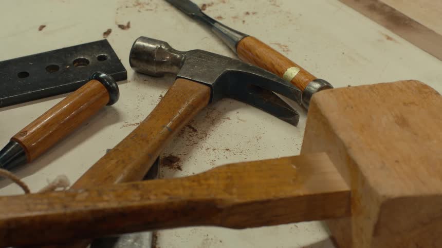 Hand placing a tool on the table next to others of a carpenter
