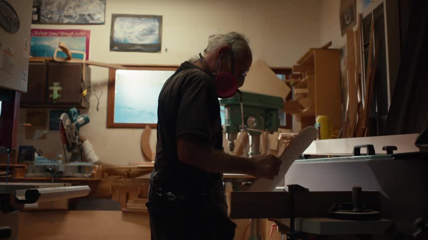 A man picks up a piece of wood in the shop
