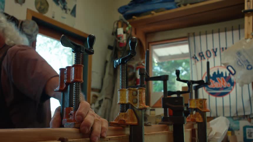 Elderly carpenter placing a tool on a wooden slat