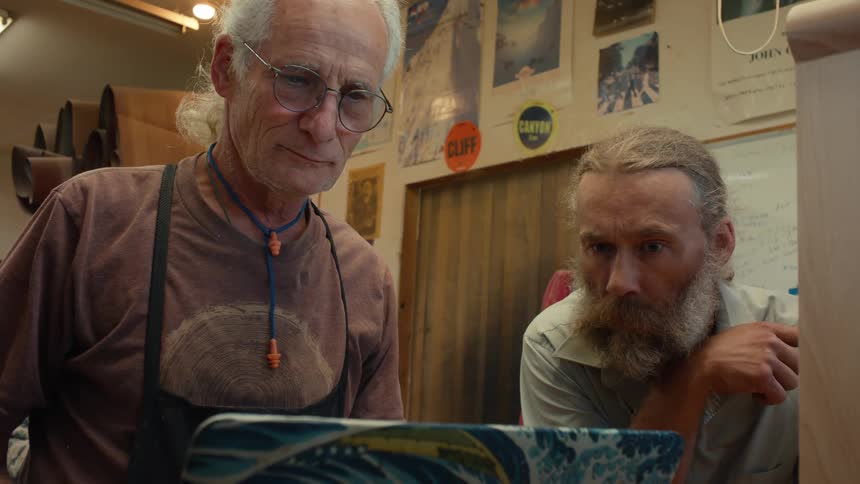Two men looking intently at the screen of an open laptop