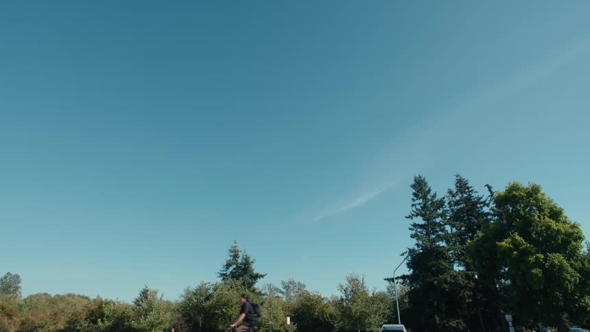 A teenage boy rides a bicycle through a parking lot