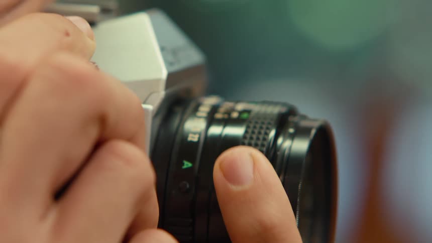 A man turns the lens adjuster on an old fashioned camera