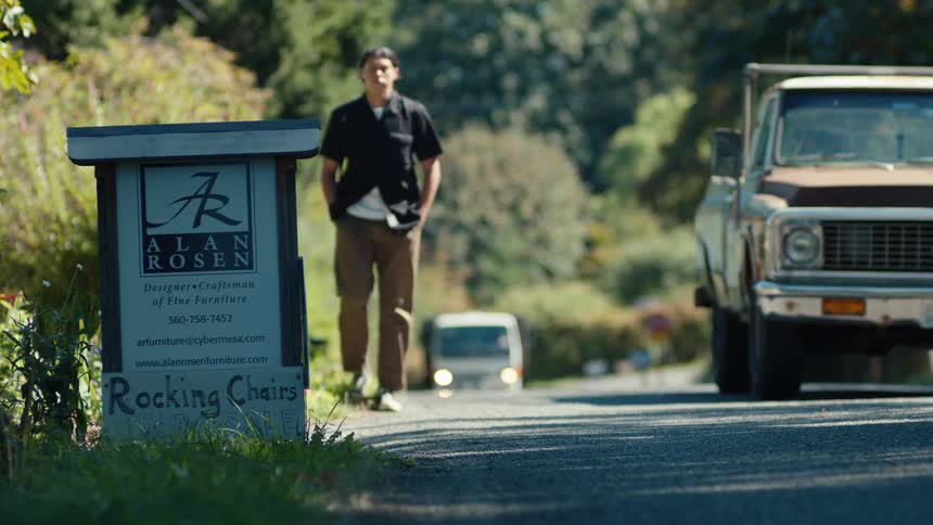 Vehicles pass a man walking on the shoulder of a road