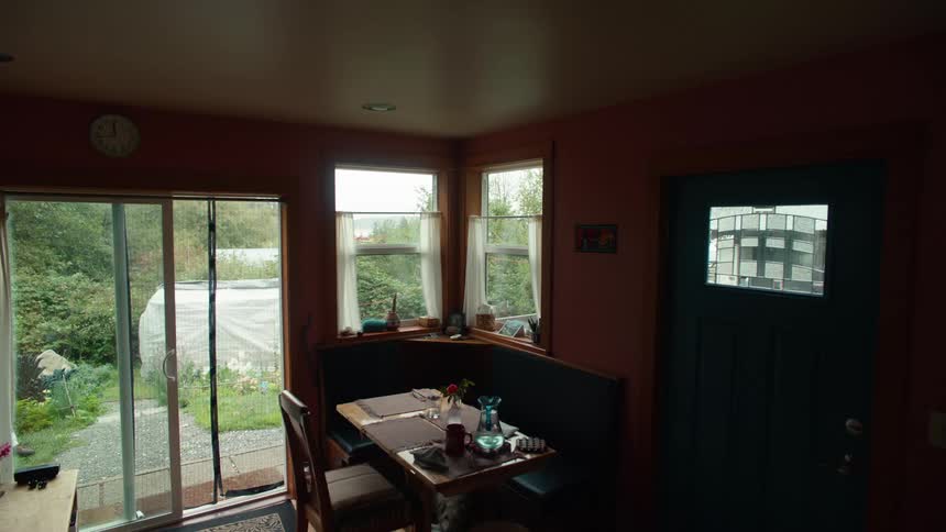 A cozy dining nook in a home with large windows offering a view of a lush garden