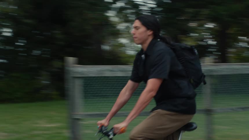 A man is riding his bicycle past a fence