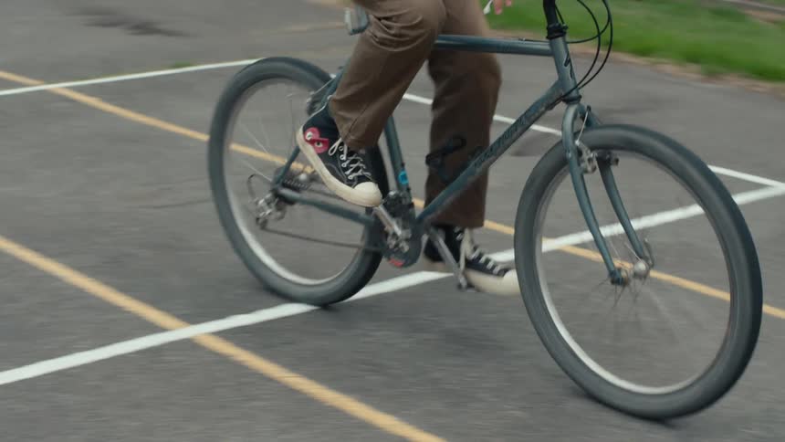 A person riding a dark gray bicycle on a ground with several white and yellow lines