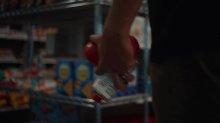 Close up of hand holding an apple and produce as you walk through the aisles of a grocery store