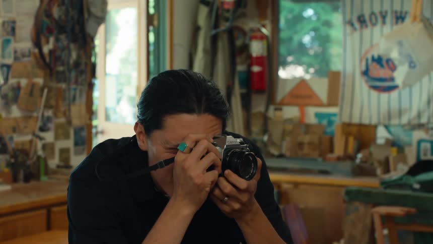 A person in a workshop focuses on taking photographs using a vintage camera