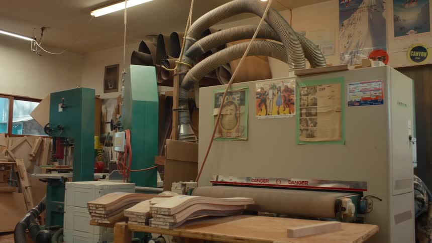 Two male carpenters working with tools in an indoor space