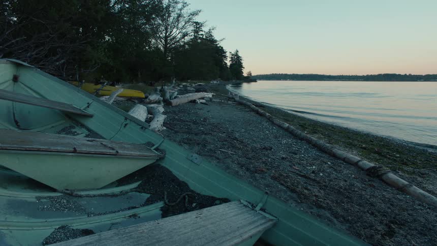 A canoe sits on a beach while the ocean lightly ripples onto the shore