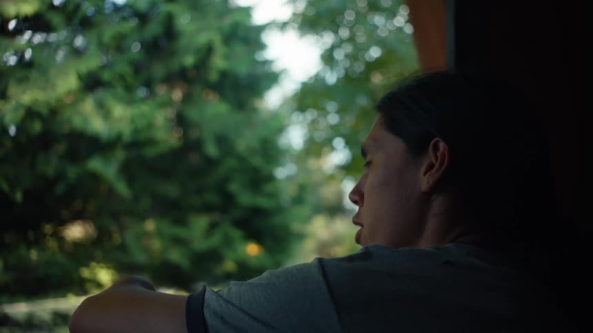 A man leans out a window and talks to someone next to him that is not shown