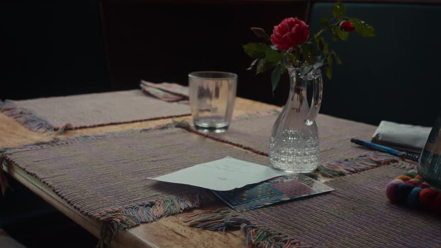 A table setting featuring a handwritten note a flower in a vase and a bingo card